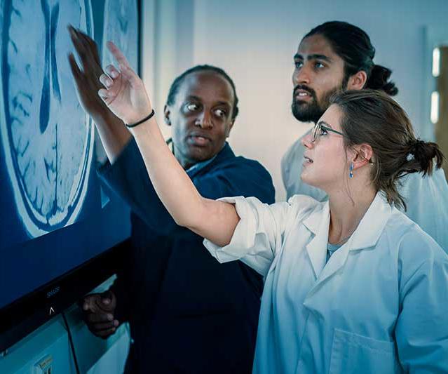 Students discussing a CT scan of a brain with Professor Peter Bazira