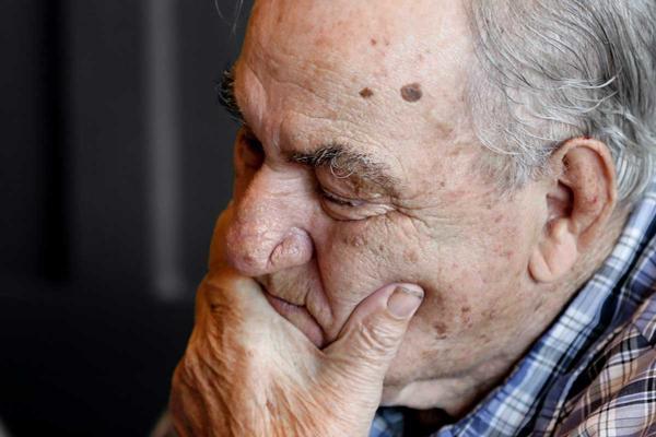 An elderly man holding his chin